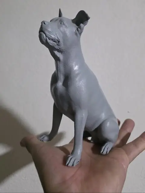 Figura 3D de pitbull en resina gris sobre la palma de una mano, antes de pintarla